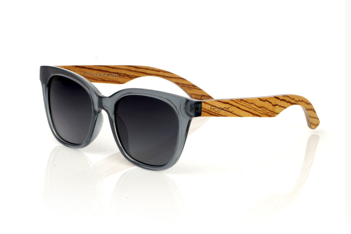 Wood eyewear of Zebrano modelo GRACE BLUE. GRACE BLUE sunglasses: elegant with a contemporary touch. These glasses, with their dark grayish blue frame, have a suggestive shape that combines rounded eyebrows with a narrower bottom, creating a sophisticated and modern look. The Zebrano wood rods provide a natural contrast, highlighting the attention to detail and quality craftsmanship. Available with gray or gradient gray lenses, they offer protection and clarity in any light. With a measurement of 143x49mm and a caliber of 50, the GRACE BLUE are ideal for those looking to stand out with subtlety and elegance. Make every look count. | Root Sunglasses® 